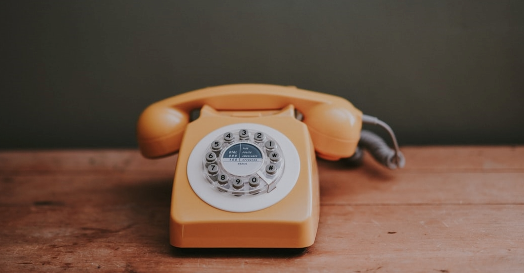 Antique Style Orange Land Line Phone on a table