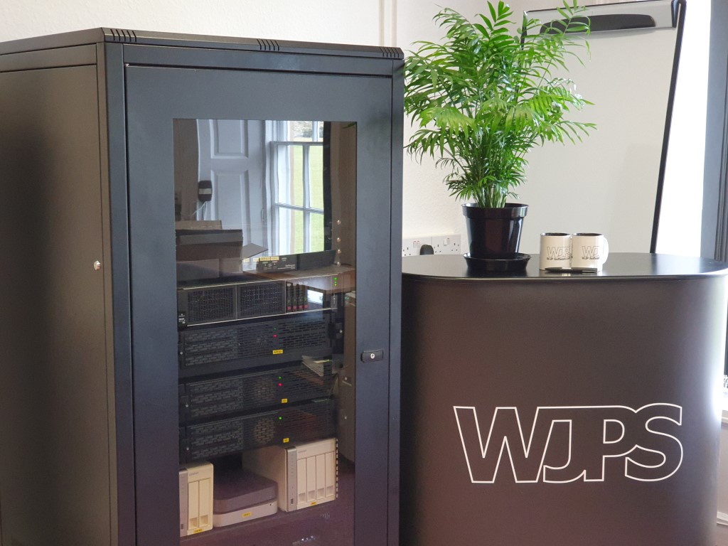 Photograph of a closed server cabinet next to a WJPS branded table and merchandise